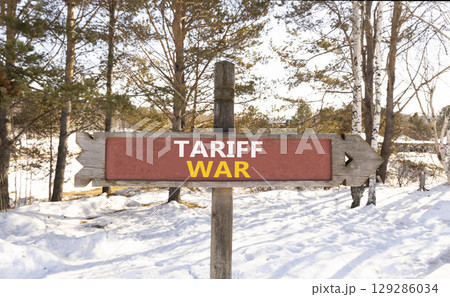Trade tariff war symbol. Concept word Tariff war on beautiful wooden road sign. Beautiful snow winter forest background. Business trade tariff wars concept. Copy space. Trade tariff war symbol. Concept word Tariff war on beautiful wooden road sign. Beautiful snow winter forest background. Business trade tariff wars concept. Copy space. 129286034