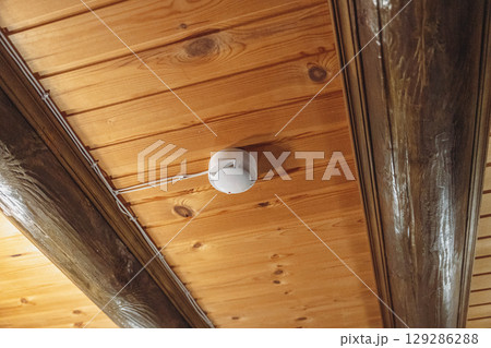 Smoke detector hanging on wooden ceiling ensuring safety 129286288
