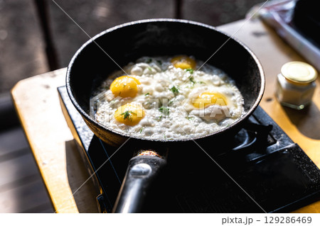 Fried eggs cooking in a pan on a portable stove Fried eggs cooking in a pan on a portable stove 129286469