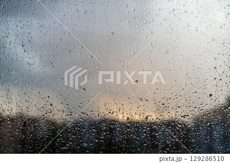 Raindrops on window with stormy sky at sunset 129286510