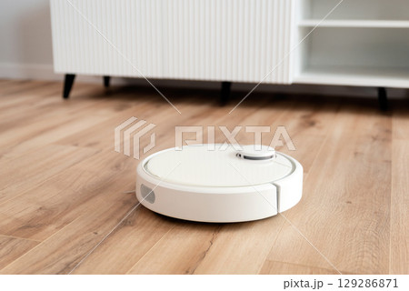 White robot vaccum cleaner in the living room White robot vaccum cleaner in the living room 129286871