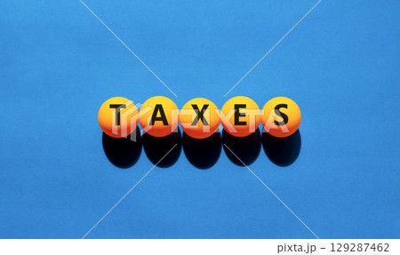 Taxes symbol. Concept word Taxes on beautiful yellow tennis ping pong balls. Beautiful wooden table wooden background. Business lifestyle taxes concept. Copy space. Taxes symbol. Concept word Taxes on beautiful yellow tennis ping pong balls. Beautiful wooden table wooden background. Business lifestyle taxes concept. Copy space. 129287462