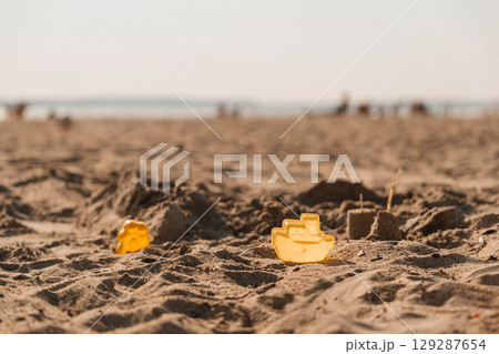 Children play with yellow sand molds on a sunny beach during summer vacation 129287654