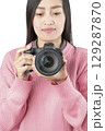 Woman Holding Black Mirrorless Camera Front View (Isolated) 129287870