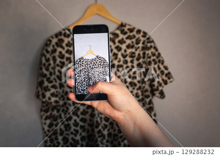 Woman taking photo of her old clothes for resale. Second hand concept. Closet organization. Woman taking photo of her old clothes for resale. Second hand concept. Closet organization. 129288232