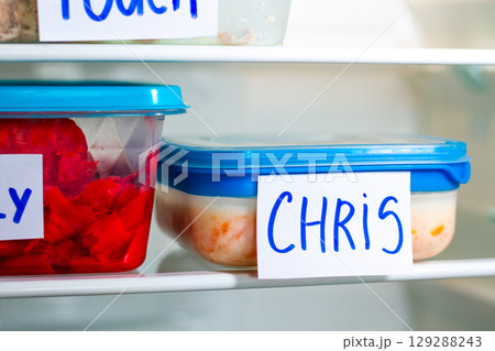 Office lunch containers with handwritten name labels in shared fridge. Healthy food preparation for work office study. 129288243