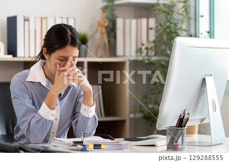 Office Syndrome: Overwhelmed woman rubbing her temples at work Office Syndrome: Overwhelmed woman rubbing her temples at work 129288555