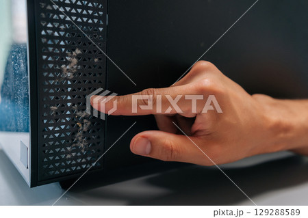 Technician pointing at thick layer of dust on computer air vents, emphasizing importance of regular cleaning and maintenance to avoid overheating and hardware failure. Concept of service PC. 129288589