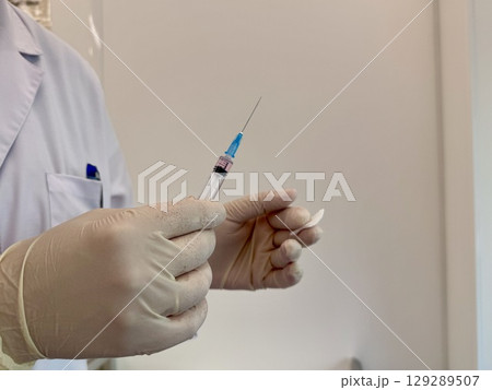 A medical officer in a white coat holds a syringe. Vaccination. High quality photo A medical officer in a white coat holds a syringe. Vaccination. High quality photo 129289507