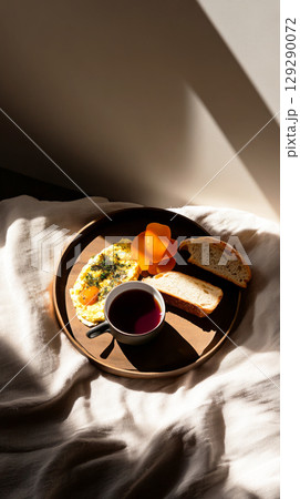 Bright morning light filters through as breakfast is served, featuring fluffy eggs, fresh bread, and a warm cup of tea, creating a serene and comforting start to the day Bright morning light filters through as breakfast is served, featuring fluffy eggs, fresh bread, and a warm cup of tea, creating a serene and comforting start to the day 129290072