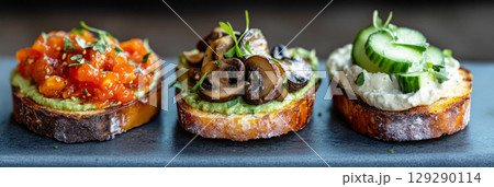 Savory breakfast spread showcases three bruschetta variations on toasted bread, each topped with fresh ingredients, herbs, and vibrant colors perfect for a morning meal 129290114