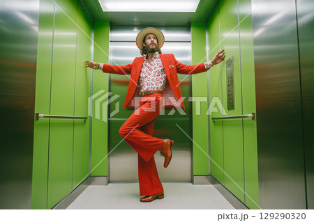 A man in a red suit and hat poses in an elevator 129290320