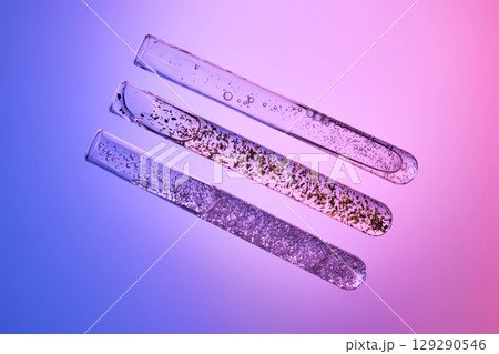 Three test tubes with different serums on a gray-purple background. 129290546