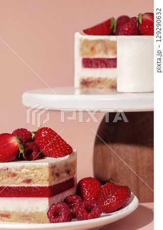 Bento cake featuring layers of vanilla sponge, raspberry, and strawberry, elegantly presented on a wooden stand, showcasing a delightful dessert and pastry menu concept with vibrant colors Bento cake featuring layers of vanilla sponge, raspberry, and strawberry, elegantly presented on a wooden stand, showcasing a delightful dessert and pastry menu concept with vibrant colors 129290632