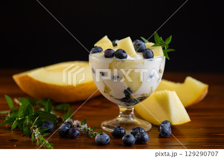 Refreshing yogurt dessert with melon and blueberries on a wooden 129290707