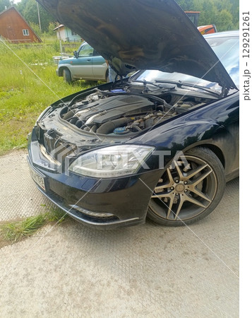 Black luxury car with an open hood representing engine trouble or maintenance 129291261