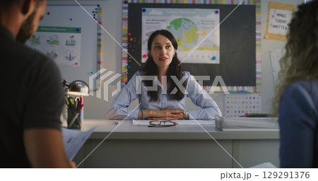 Female Teacher Discussing Academic Progress and Grades of Pupil with His Parents 129291376