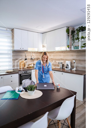 Female Doctor Preparing Laptop for Telemedicine in Kitchen Female Doctor Preparing Laptop for Telemedicine in Kitchen 129291458