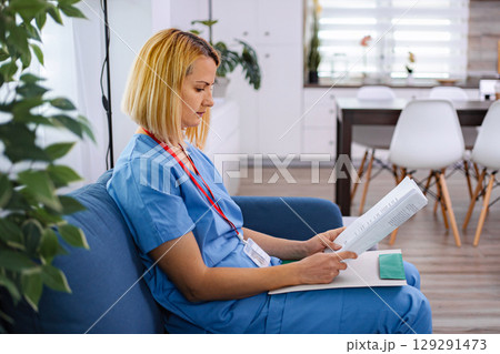 Young female doctor is reading medical records of her patient Young female doctor is reading medical records of her patient 129291473