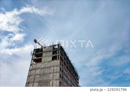 Construction of multi-story building with load-bearing frame made of monolithic reinforced concrete and gas blocks walls. Special protective nets stretched to prevent workers and objects from falling Construction of multi-story building with load-bearing frame made of monolithic reinforced concrete and gas blocks walls. Special protective nets stretched to prevent workers and objects from falling 129291796
