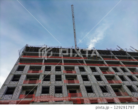 View from below of construction of multi-story building with load-bearing monolithic reinforced concrete frame, gas blocks walls. Special protective nets stretched to prevent workers from falling View from below of construction of multi-story building with load-bearing monolithic reinforced concrete frame, gas blocks walls. Special protective nets stretched to prevent workers from falling 129291797