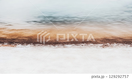 Coastal shoreline with sandy beach and calm water at sunrise in a serene natural landscape 129292757