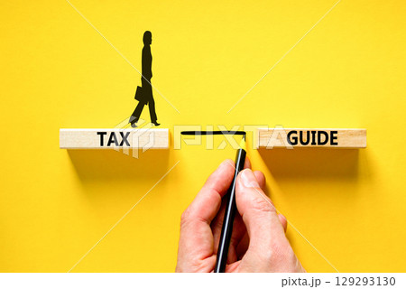 Tax guide symbol. Concept words Tax guide on beautiful wooden block. Beautiful yellow table yellow background. Businessman hand. Businesswoman icon. Business and Tax guide concept. Copy space. Tax guide symbol. Concept words Tax guide on beautiful wooden block. Beautiful yellow table yellow background. Businessman hand. Businesswoman icon. Business and Tax guide concept. Copy space. 129293130