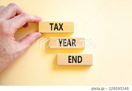 Tax year end symbol. Concept words Tax year end on beautiful wooden blocks. Beautiful white background. Businessman hand. Business tax year end concept. Copy space. Tax year end symbol. Concept words Tax year end on beautiful wooden blocks. Beautiful white background. Businessman hand. Business tax year end concept. Copy space. 129293148