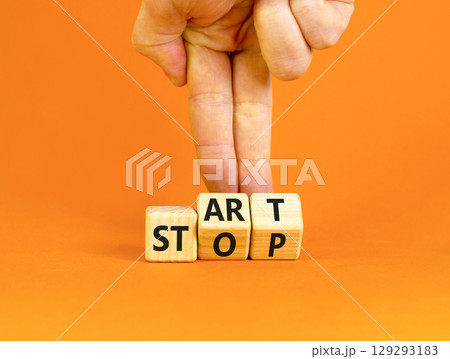 Start or stop symbol. Concept words Start or Stop on beautiful wooden block. Beautiful orange table orange background. Businessman hand. Business start or stop concept. Copy space. 129293183
