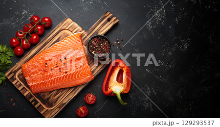 Fresh raw salmon fillet with cooking ingredients on wooden board top view on black background 129293537