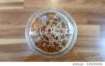 Top View of Iced Coffee in a Plastic Cup on a Wooden Table Top View of Iced Coffee in a Plastic Cup on a Wooden Table 129294260