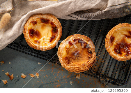 Golden pastel de nata pastries cooling on a black wire rack Golden pastel de nata pastries cooling on a black wire rack 129295890
