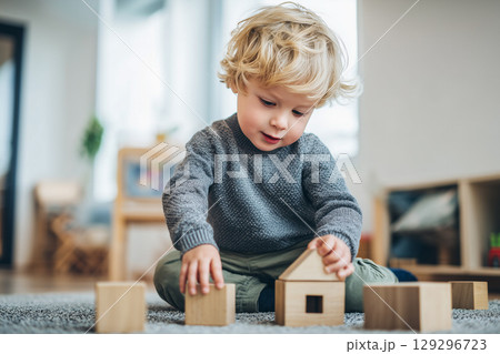 Joyful Child Engaged in Play with Wooden Toys on Soft Carpet in Bright Indoor Environment Joyful Child Engaged in Play with Wooden Toys on Soft Carpet in Bright Indoor Environment 129296723
