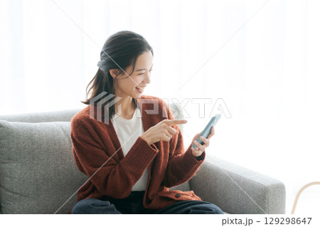 ソファーでスマホを使う若い女性 ソファーでスマホを使う若い女性 129298647