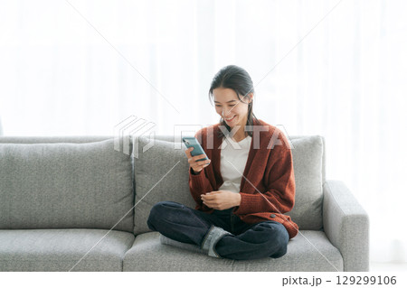 ソファでスマホを使う女性 ソファでスマホを使う女性 129299106