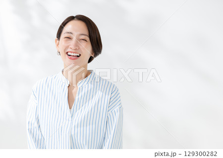 木漏れ日の中に立つ笑顔の女性 129300282