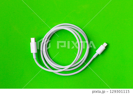 Cable with Type-C connector insulated, charging cable coiled on a green background. Cable with Type-C connector insulated, charging cable coiled on a green background. 129301115