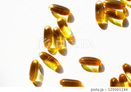 Golden fish oil capsules on white background. Golden fish oil capsules on white background. 129301194