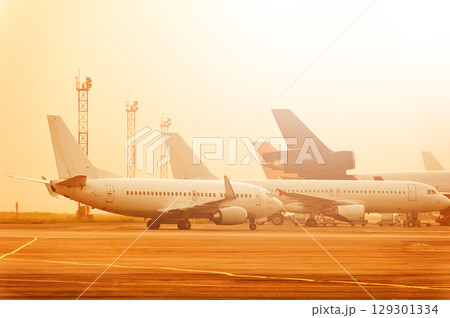 Many planes are standing at the airport at a beautiful sunset. Many planes are standing at the airport at a beautiful sunset. 129301334