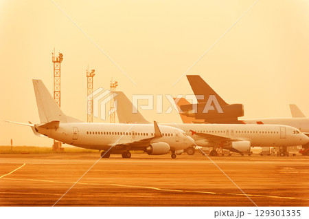 Many planes are standing at the airport at a beautiful sunset. Many planes are standing at the airport at a beautiful sunset. 129301335
