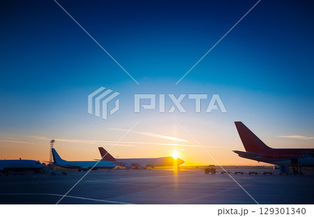 Many planes are standing at the airport at a beautiful sunset. Many planes are standing at the airport at a beautiful sunset. 129301340