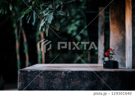 Flower in a pot placed on a stone table surrounded by lush greenery at dusk 129301840