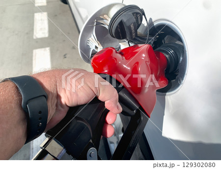 Male Hand Holding Gas Pump Nozzle Pumping Gas Into Vehicle. 129302080