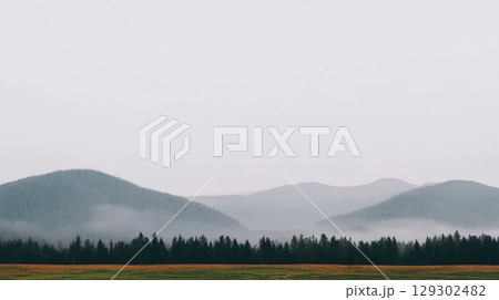Serene landscape with misty mountains and calm hills during overcast weather 129302482