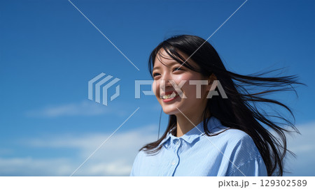 日本人女性が青空の下で笑顔を見せる 129302589