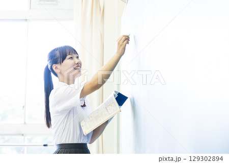 黒板に文字を書く女子高生 129302894