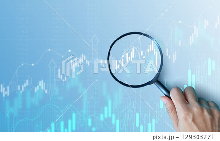 Hand holding magnifying glass analyzing digital financial stock chart. Data analysis, investment research, trading strategy, and financial market concept on blue background. business stock market. Hand holding magnifying glass analyzing digital financial stock chart. Data analysis, investment research, trading strategy, and financial market concept on blue background. business stock market. 129303271