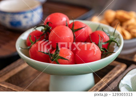Fresh red tomatoes displayed on a light green bowl 129303313