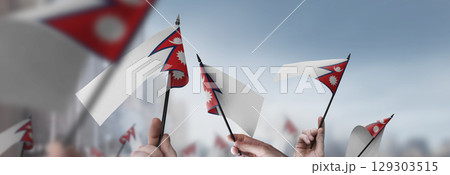 Nepal flags in their hands on a blurred urban background Nepal flags in their hands on a blurred urban background 129303515