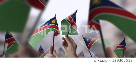 Namibia flags in their hands on a blurred urban background 129303518
